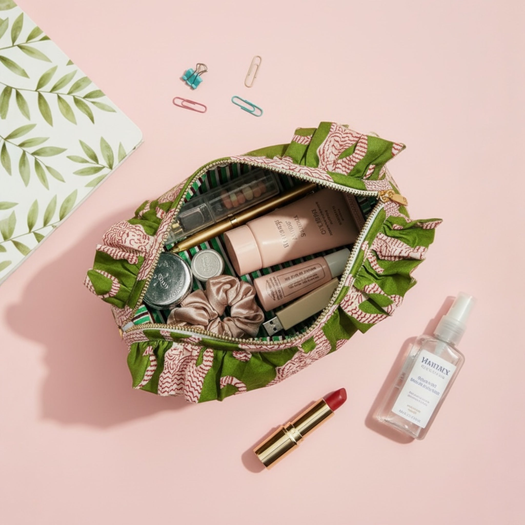 Makeup bag with various cosmetic items on a pink background